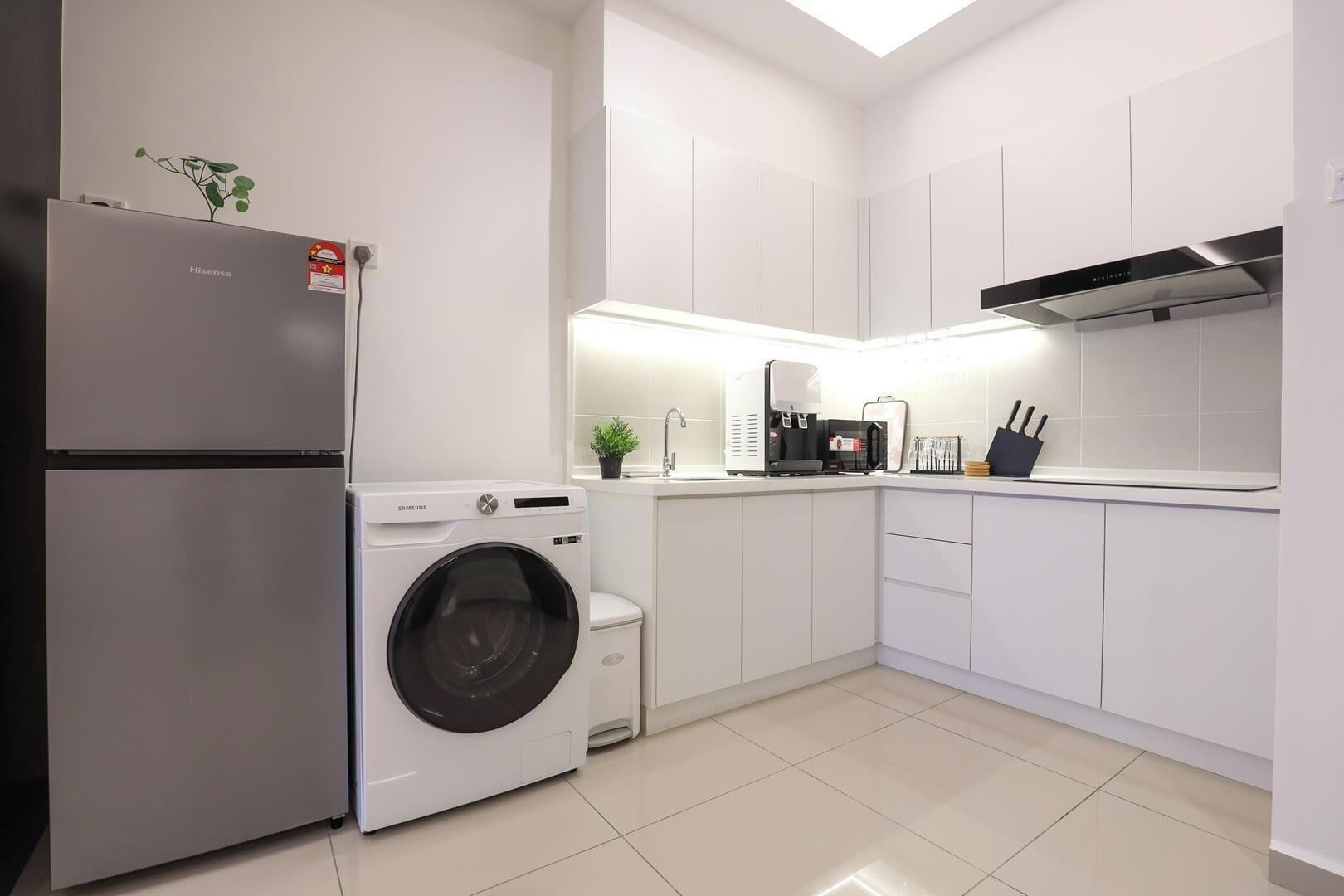 A modern kitchen with a built-in washer, a refrigerator, and a microwave.