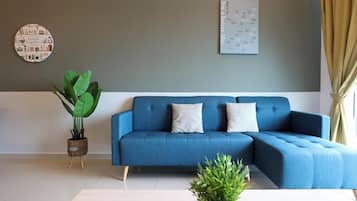 Una sala moderna con un sofá seccional azul, dos cojines decorativos, una obra de arte redonda en la pared y una planta en maceta.