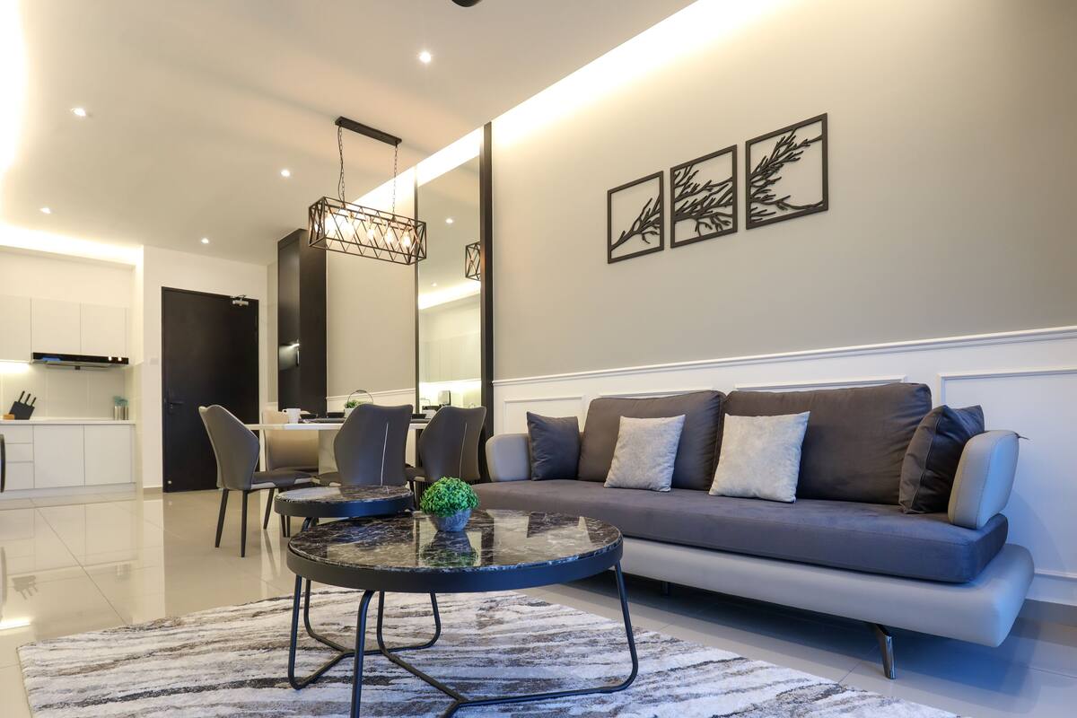 A modern living room with a sofa, chairs, a coffee table, and a dining area in the background.