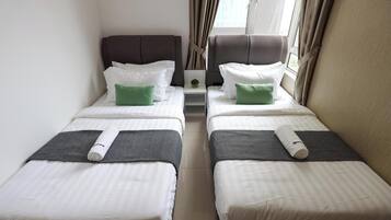 Ein Doppelzimmer mit zwei Betten, jeweils mit Kissen, einem Nachttisch und einem Vorhangfenster.