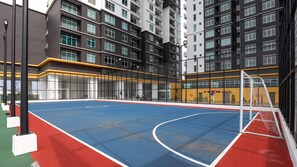 An indoor basketball court with a net, surrounded by a high fence and adjacent to a multi-story building with balconies. - NOVO 8 Jonker Street Melaka By I Housing (Malacca City)