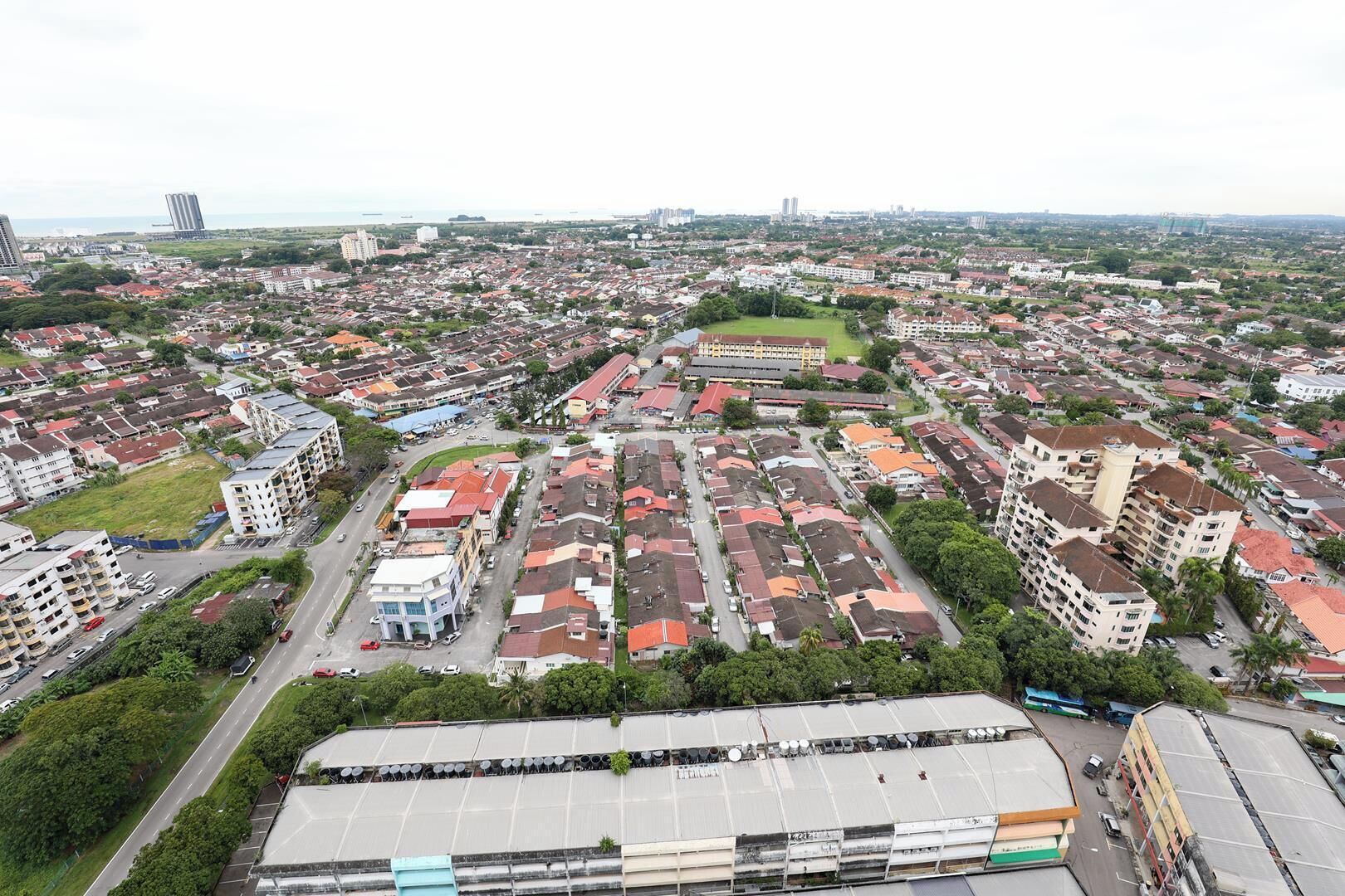 An aerial view of a residential area with multiple buildings, roads, and green spaces.