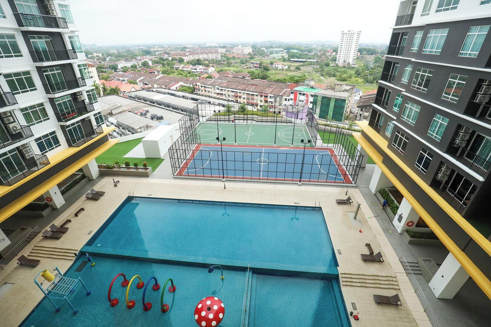A rooftop pool with a basketball court, surrounded by high-rise buildings.