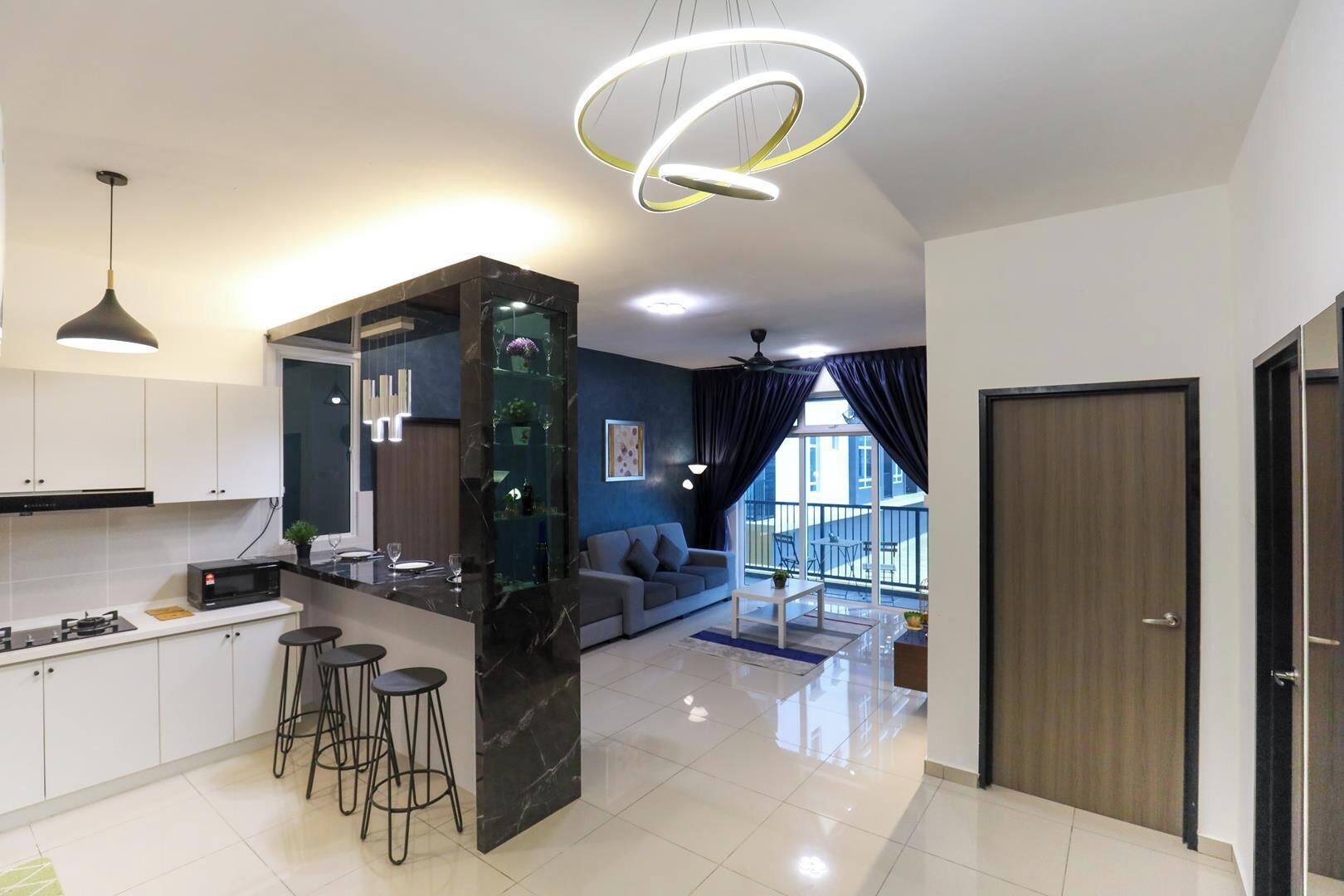 A modern kitchen with a marble island, bar stools, and a dining area with a sofa.