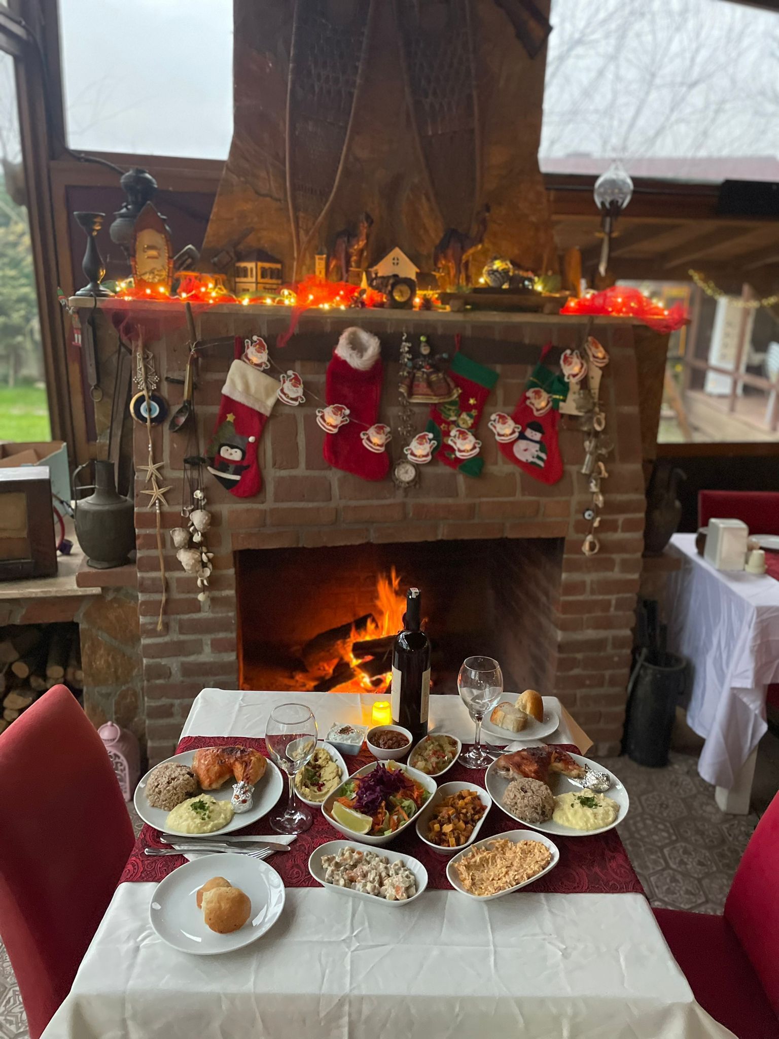 A dining table set with various dishes and a fireplace with Christmas decorations.
