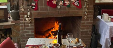 A dining table set with various dishes and a fireplace with Christmas decorations.