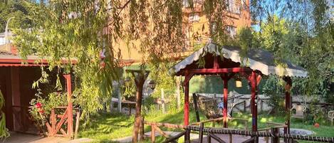 Un jardin avec des chaises en osier, une petite table et un kiosque.