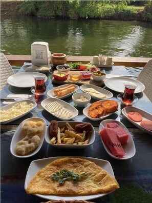 A table set with various dishes and drinks, overlooking a body of water. - Agva Kapim Hotel (Sile)