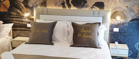 Uma cama com cobertura acolchoada, duas almofadas com texto e uma parede com um mural floral.