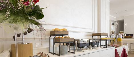 Montaje de bufé con diversas opciones de comida y un arreglo floral decorativo.