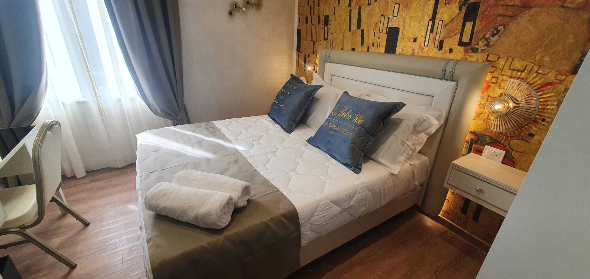 A neatly made bed with two pillows, a bedside table with a lamp, and a chair.