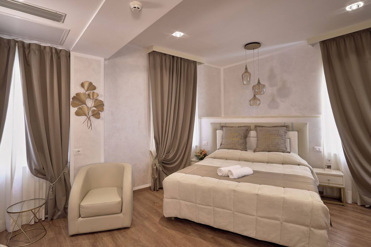 A modern bedroom with a large bed, a chair, and a nightstand.