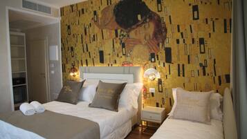 Une chambre d’hôtel avec deux lits, un grand tableau au mur et une table de chevet avec une lampe.