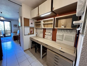 Cozinha com armários de madeira, bancada e painel perfurado com ganchos.