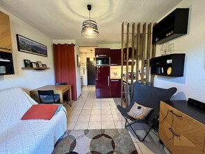 A compact living space with a dining area, kitchenette, and a seating area with a sofa and a chair.