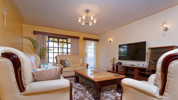 A living room with a sofa, armchairs, a coffee table, a TV, and a chandelier.