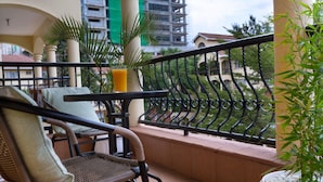 A balcony with wicker furniture, a potted plant, and a glass of orange juice.