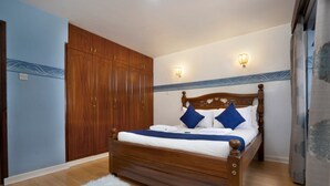 A bedroom with a wooden bed, blue pillows, and a white fluffy rug.