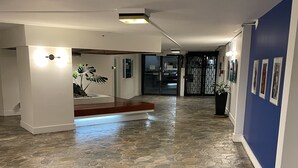 A spacious hallway with a stone-patterned floor, white walls, and a blue accent wall. - Modern Ocean View Studio - Waikiki Paradise! (Honolulu)