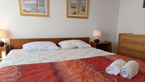 A hotel room with a large bed, two paintings on the wall, a wooden dresser, and a nightstand with a lamp. - Sea view apartment in Notre-Dame-de-Monts - 5 people, pets (Notre-Dame-de-Monts)