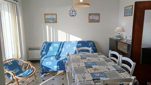 A room with a bed, a chair, a table, and a lamp. There are pictures on the wall and a window with curtains. - Sea view apartment in Notre-Dame-de-Monts - 5 people, pets (Notre-Dame-de-Monts)