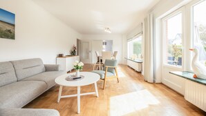 Una sala de estar moderna con un sofá gris, una mesa de centro redonda y un comedor con una silla y una mesa.