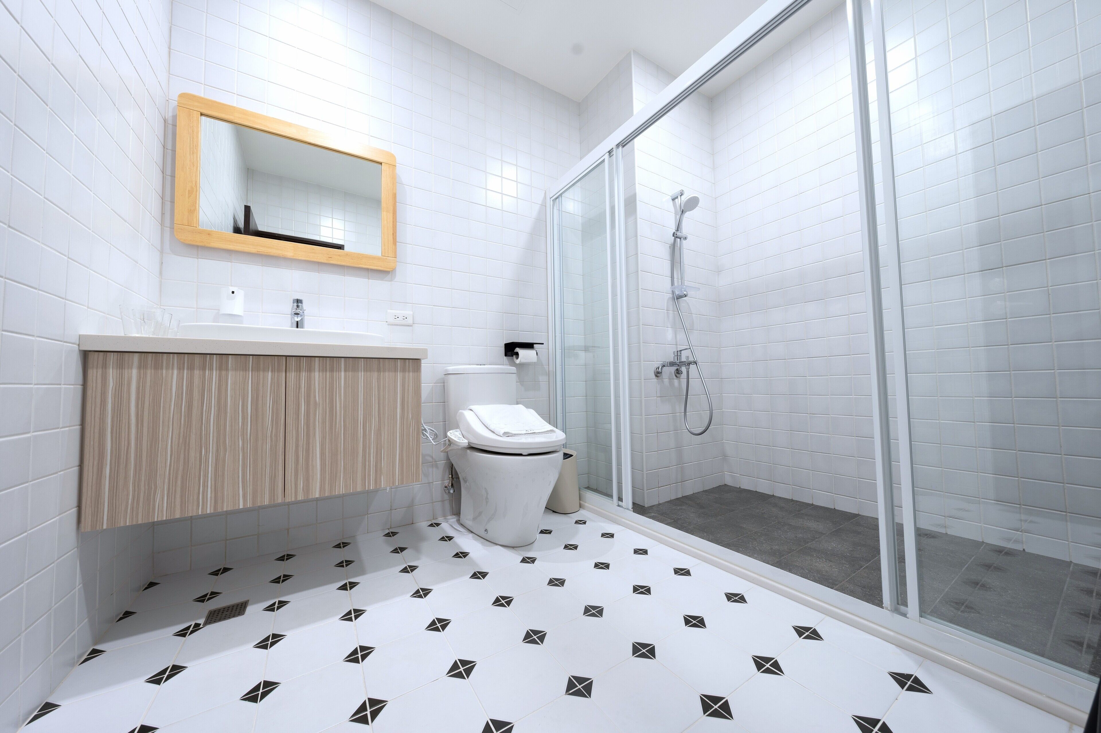 A bathroom with a toilet, sink, mirror, and shower.