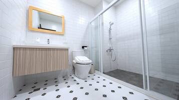 A bathroom with a toilet, sink, mirror, and shower.