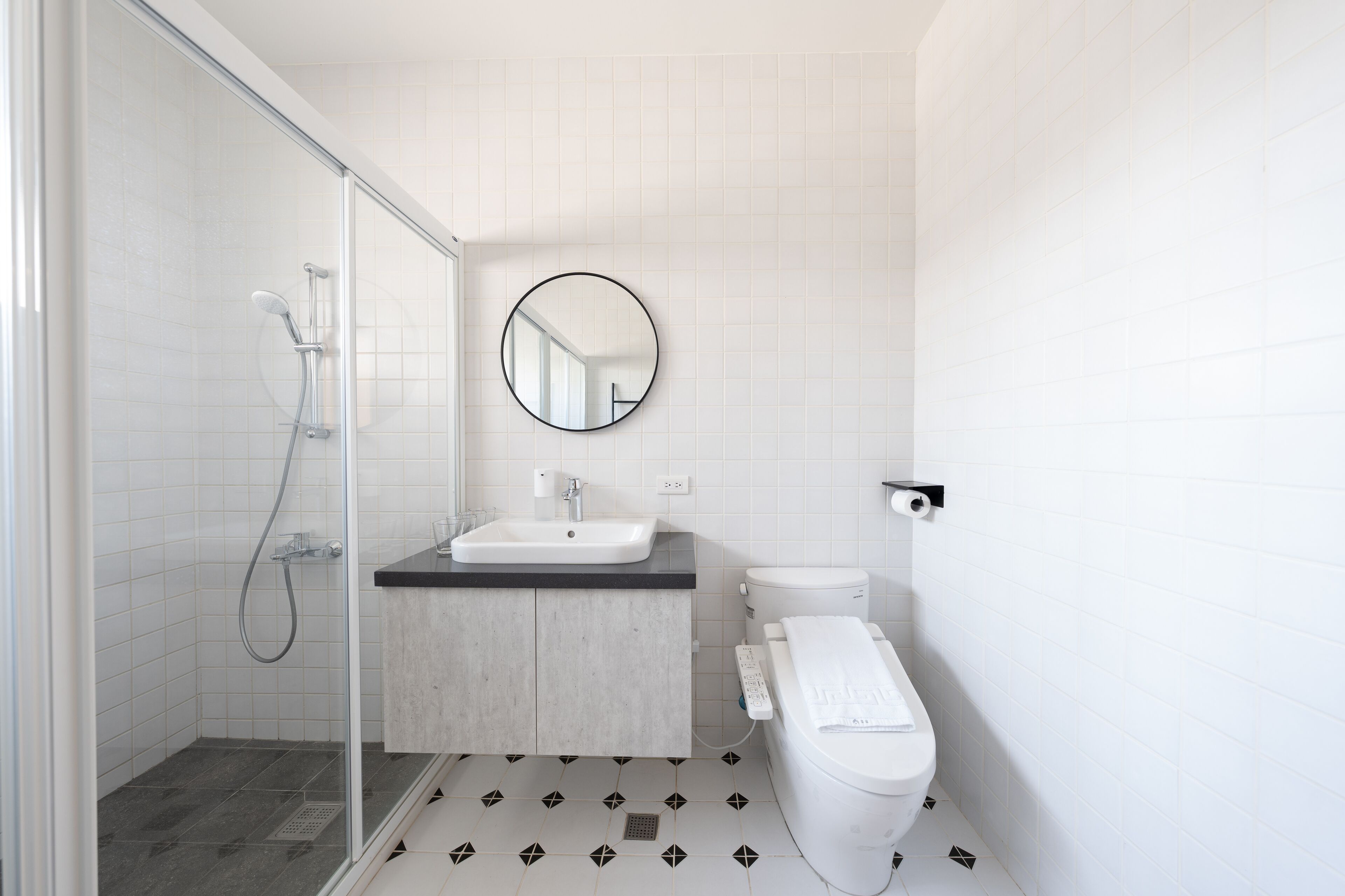 A modern bathroom with a glass shower enclosure, a sink, and a toilet.