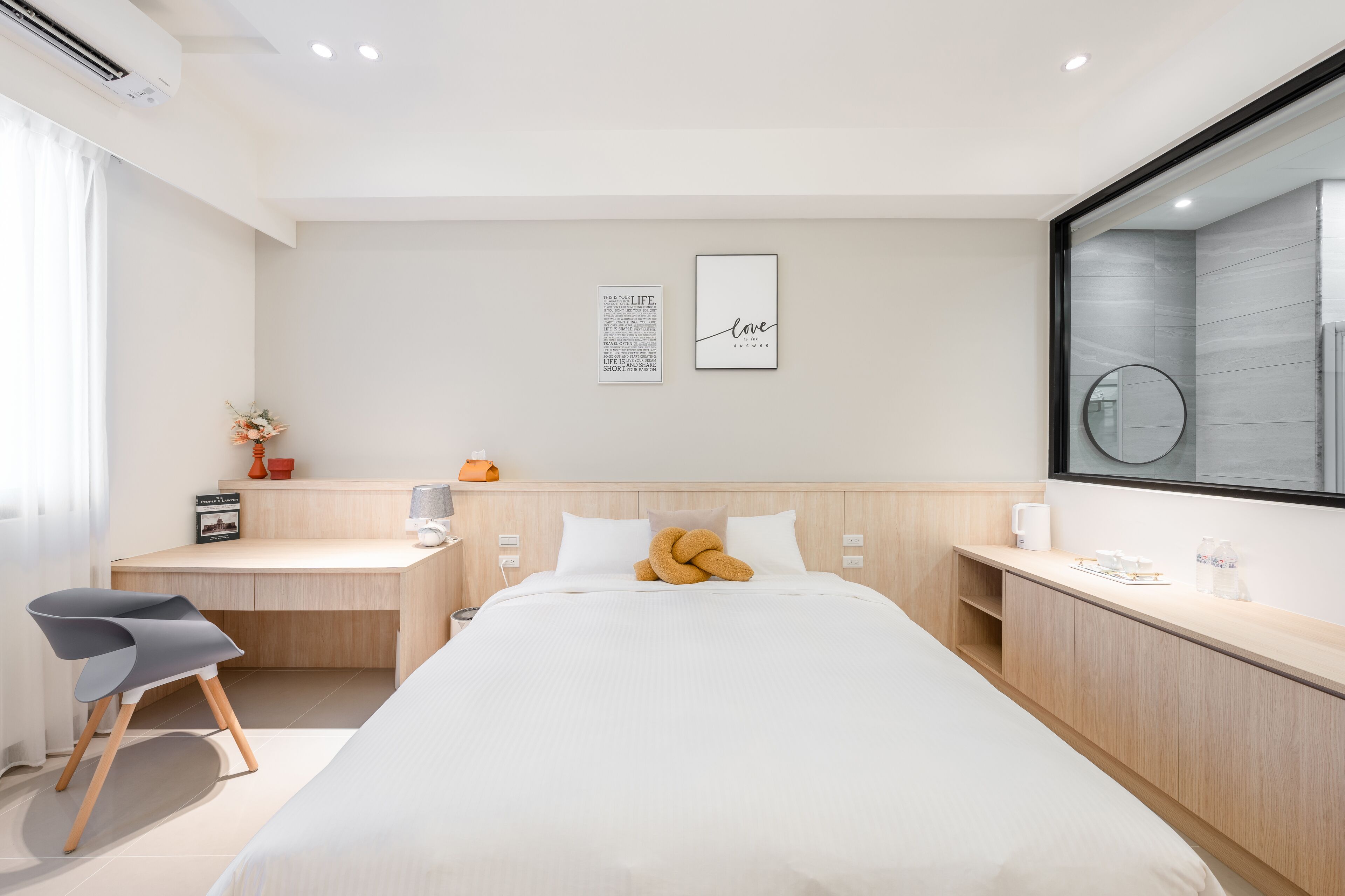 A modern hotel room with a bed, a desk, and a large mirror.