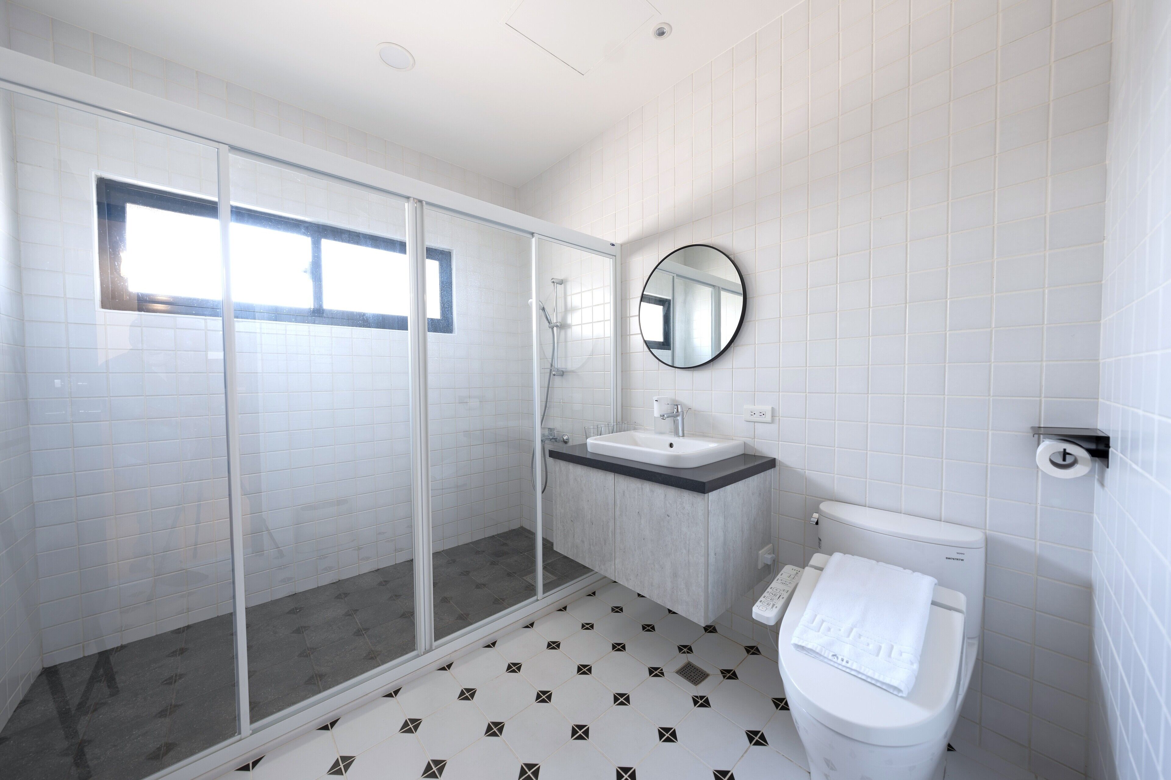 Un baño moderno con cabina de ducha de vidrio, un lavamanos y un inodoro.