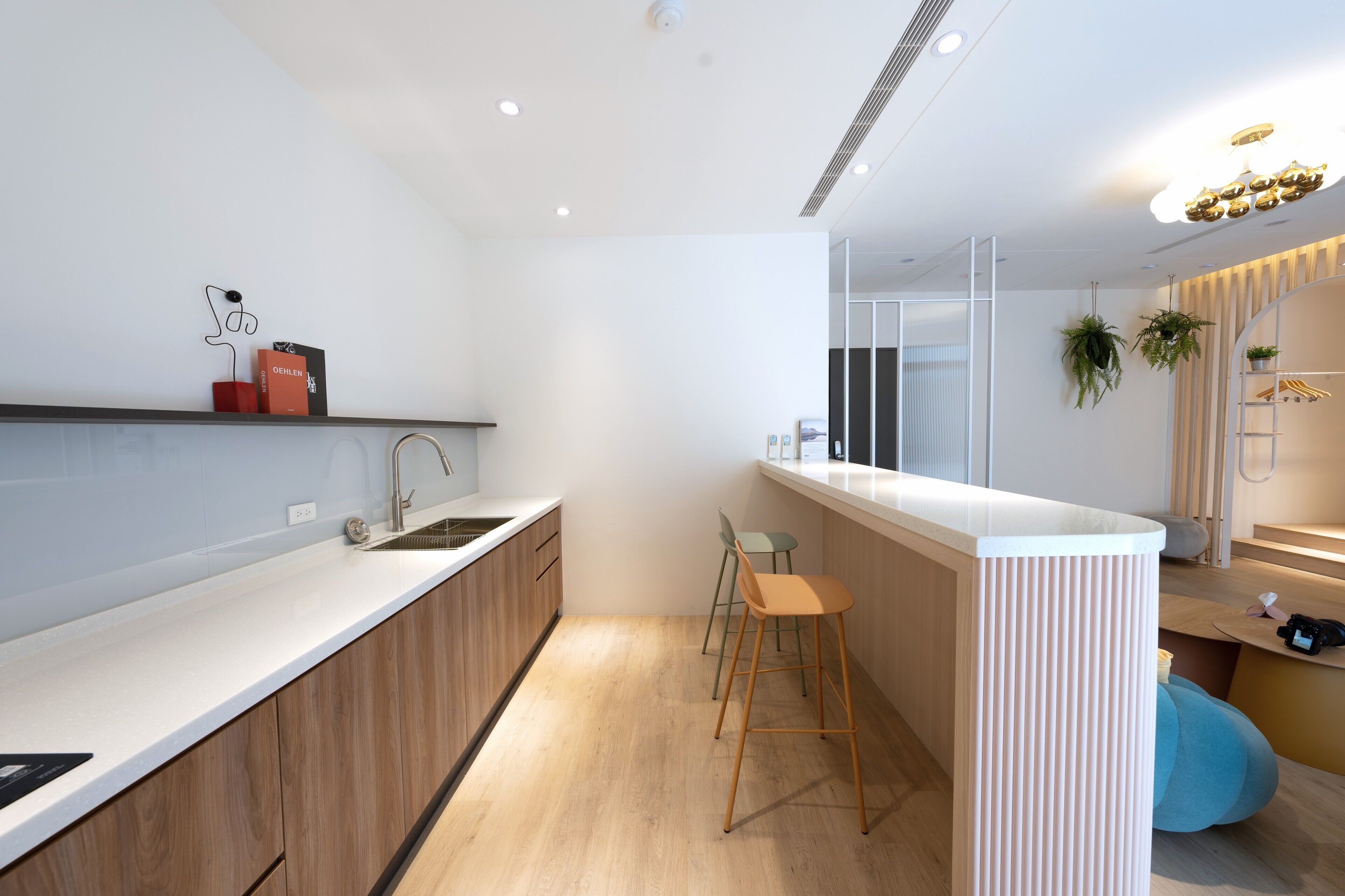 A modern kitchen with a white countertop, wooden cabinets, and a bar area with stools.