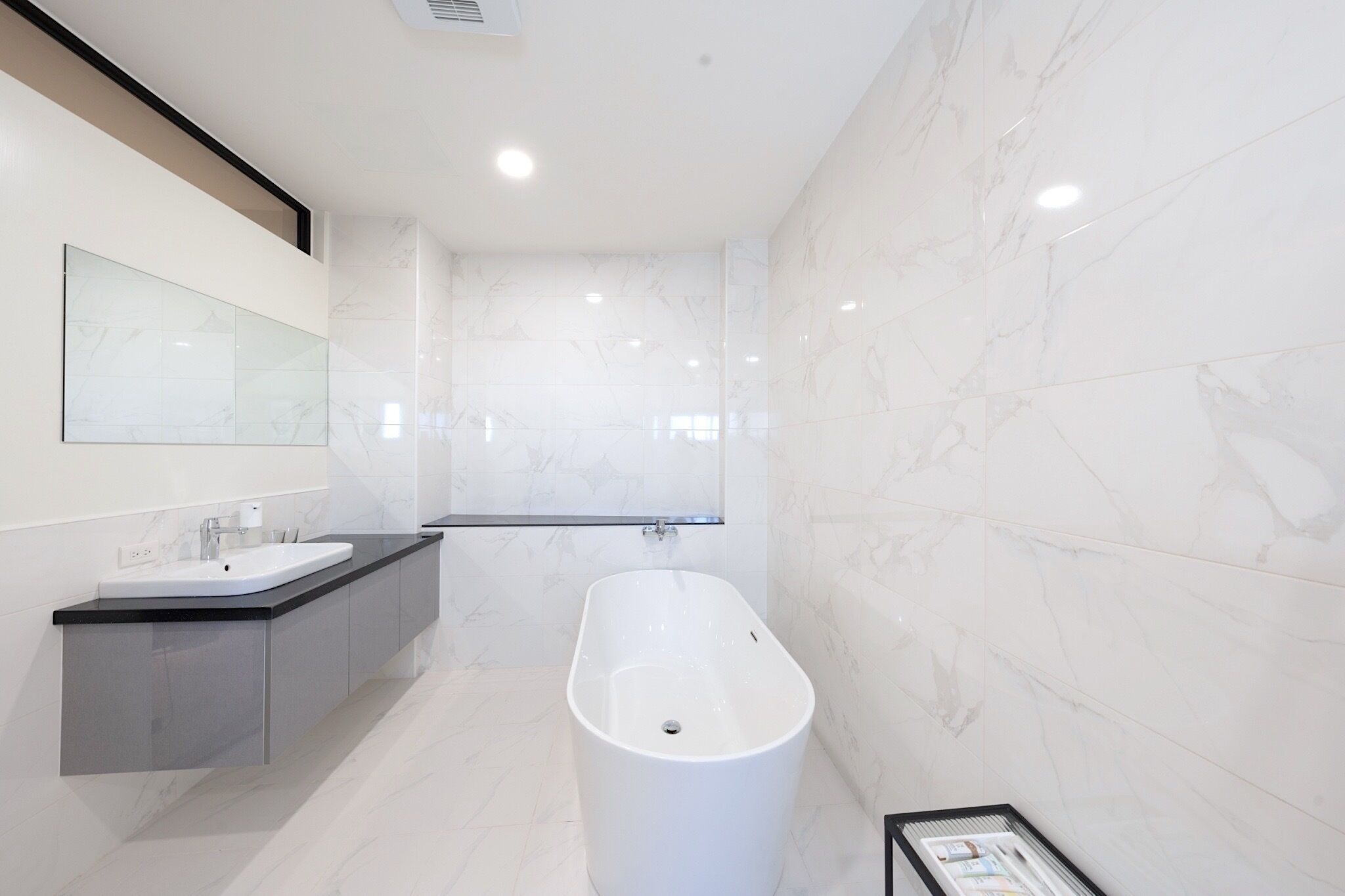 Un baño moderno con una bañera independiente, un espejo grande y un tocador con lavabo.