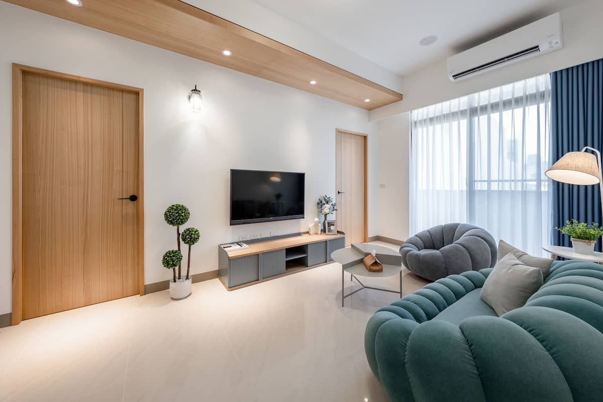Una sala de estar moderna con un televisor de pantalla plana, un sofá gris y un techo de madera.