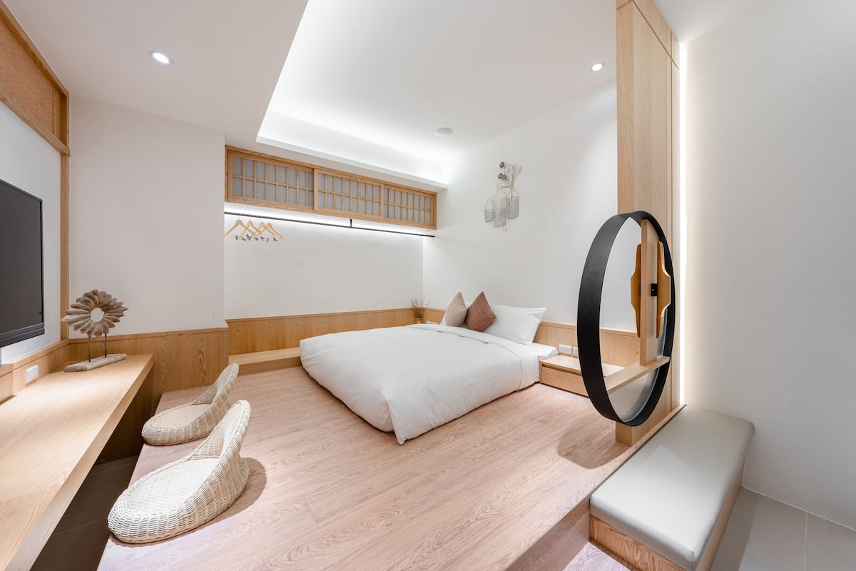 Una habitación de hotel moderna con tragaluz, una cama con ropa de cama blanca, un escritorio de madera y un espejo grande.