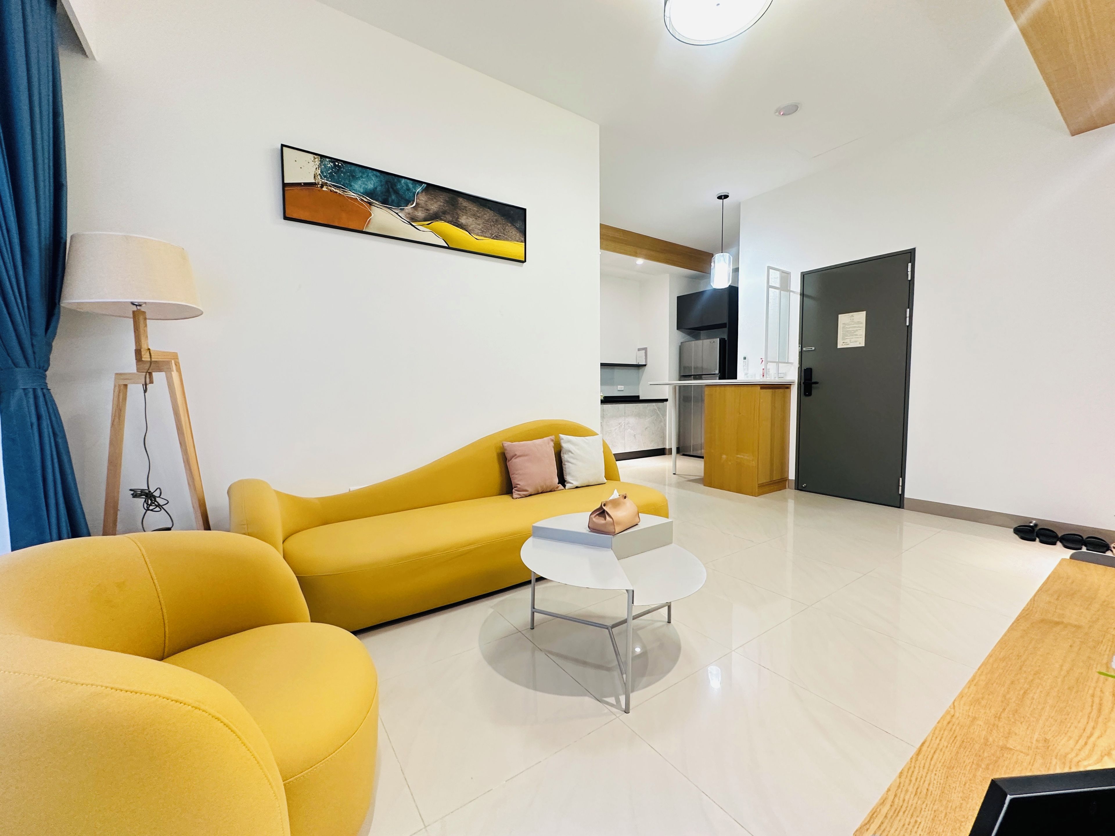 Ein modernes Wohnzimmer mit einem gelben Sofa, einem kleinen weißen Couchtisch und einem Bild an der Wand.