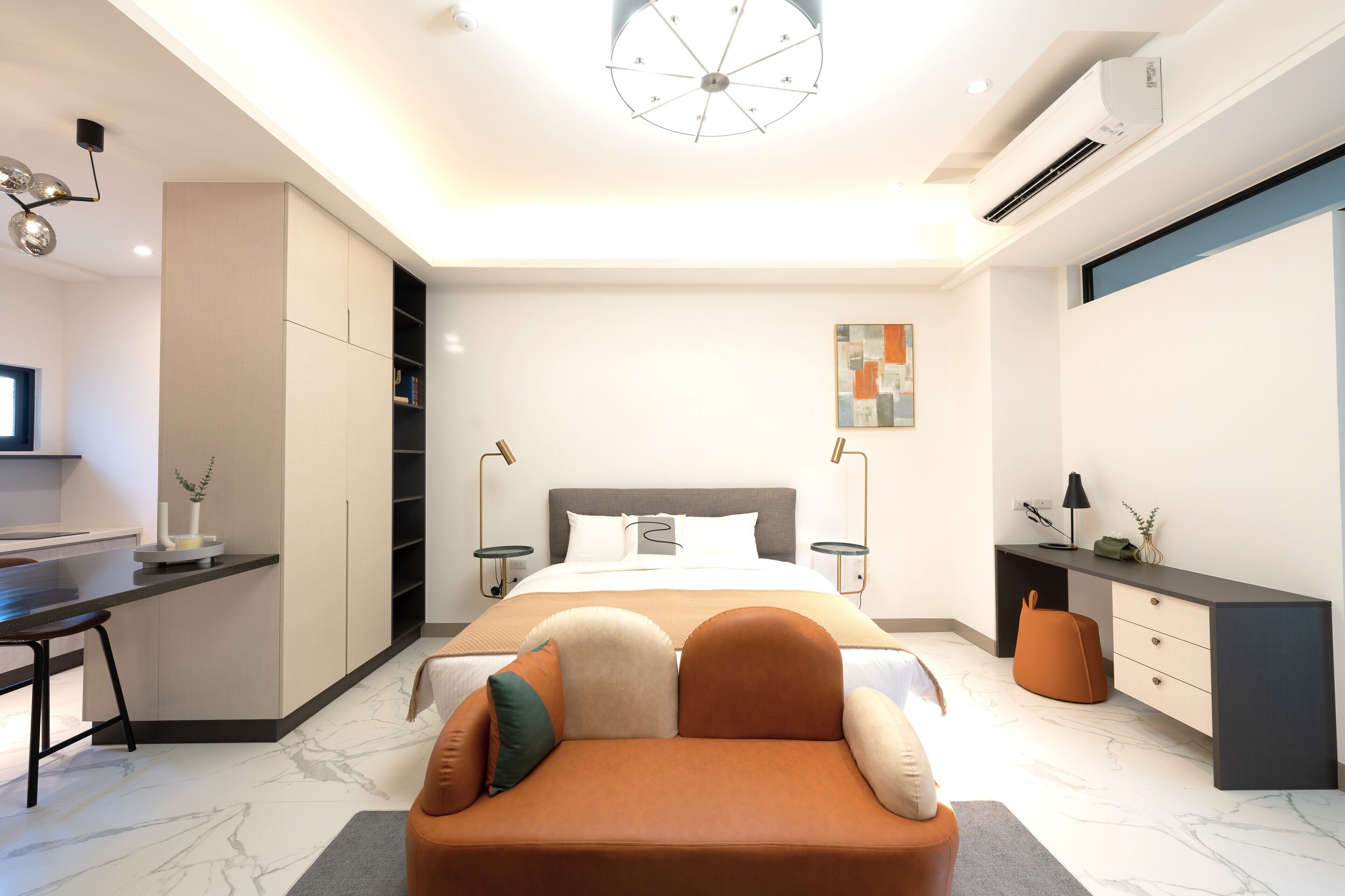 A modern bedroom with a bed, bedside tables, a desk, and a sofa.