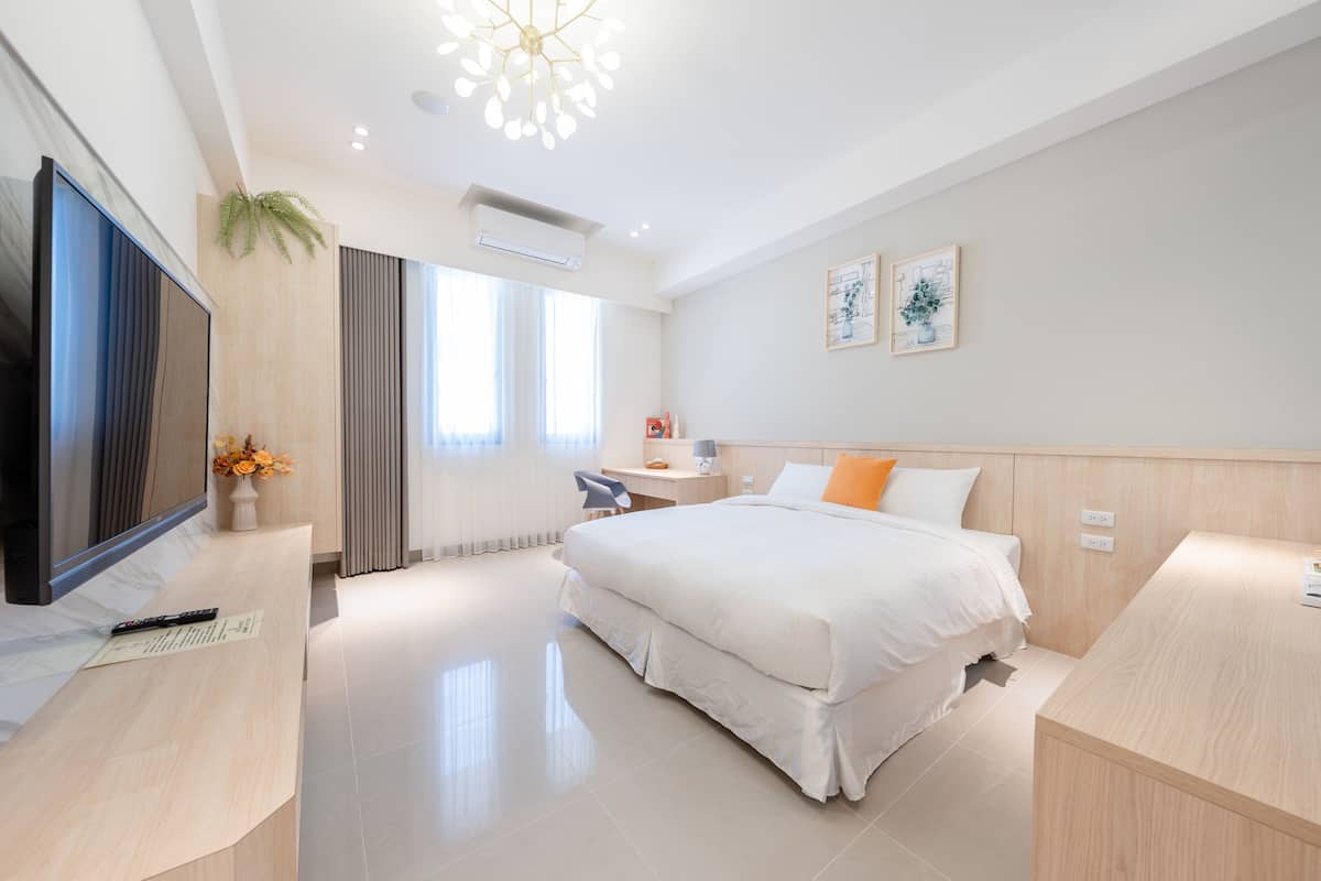 Una habitación de hotel moderna con una cama grande, un escritorio, un televisor y una planta.