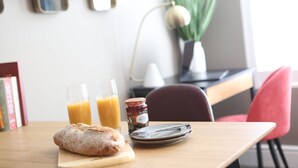 A breakfast setup with a loaf of bread, two glasses of orange juice, and a jar of jam on a wooden table. - Cathedral Superior Apartment (Worcestershire)