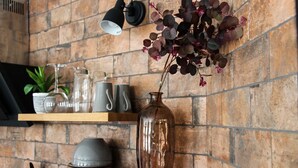 A kitchen with a brick wall, wooden shelves, a vase with flowers, and kitchen utensils. - Cathedral Superior Apartment (Worcestershire)