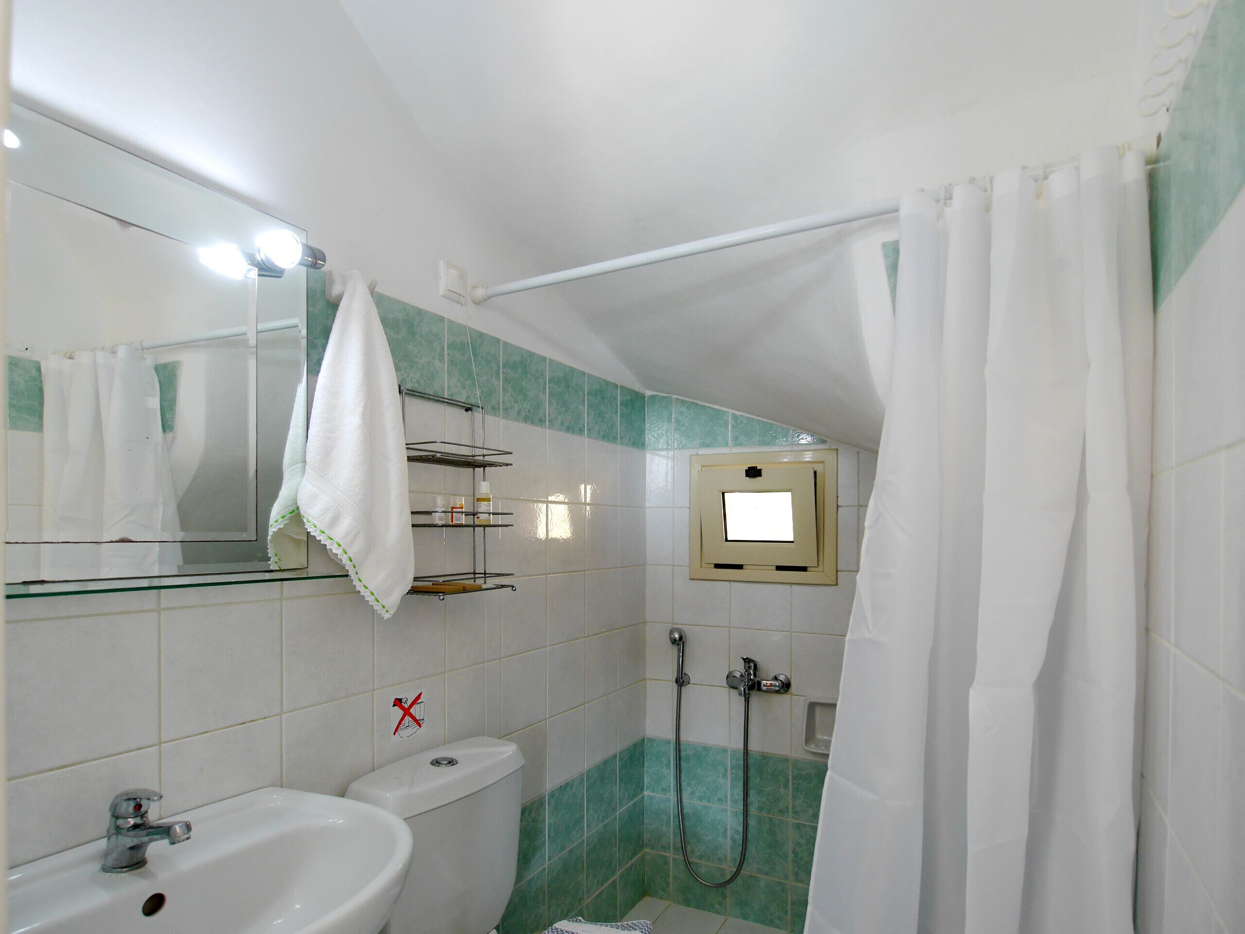 A bathroom with a sink, toilet, shower, and a mirror with lights.