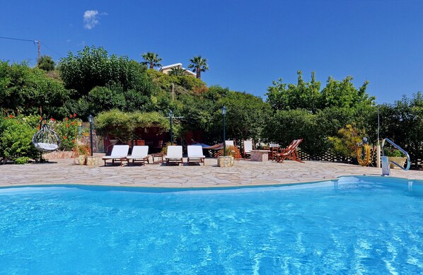 A swimming pool with lounge chairs and a stone pathway.