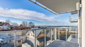 A balcony with a clear view of a residential area and a distant shoreline.