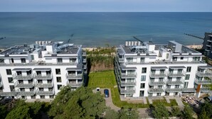 A modern apartment complex with multiple balconies, a central courtyard, and a view of the sea.