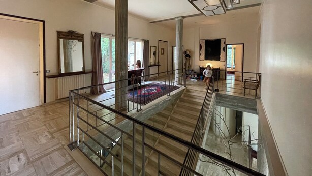 Un interior espacioso con una escalera, un ventanal grande y una lámpara moderna.