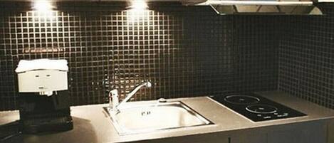 Una cucina moderna con mobili scuri, un lavello in acciaio inossidabile e un forno a microonde sopra il piano cottura.