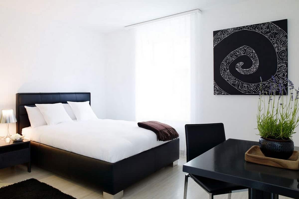 Une chambre moderne avec un lit, une table de chevet, une lampe et une œuvre d’art accrochée au mur.