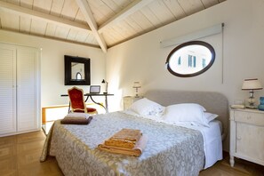 Une chambre à coucher avec un lit, une fenêtre ronde, un bureau et une armoire.