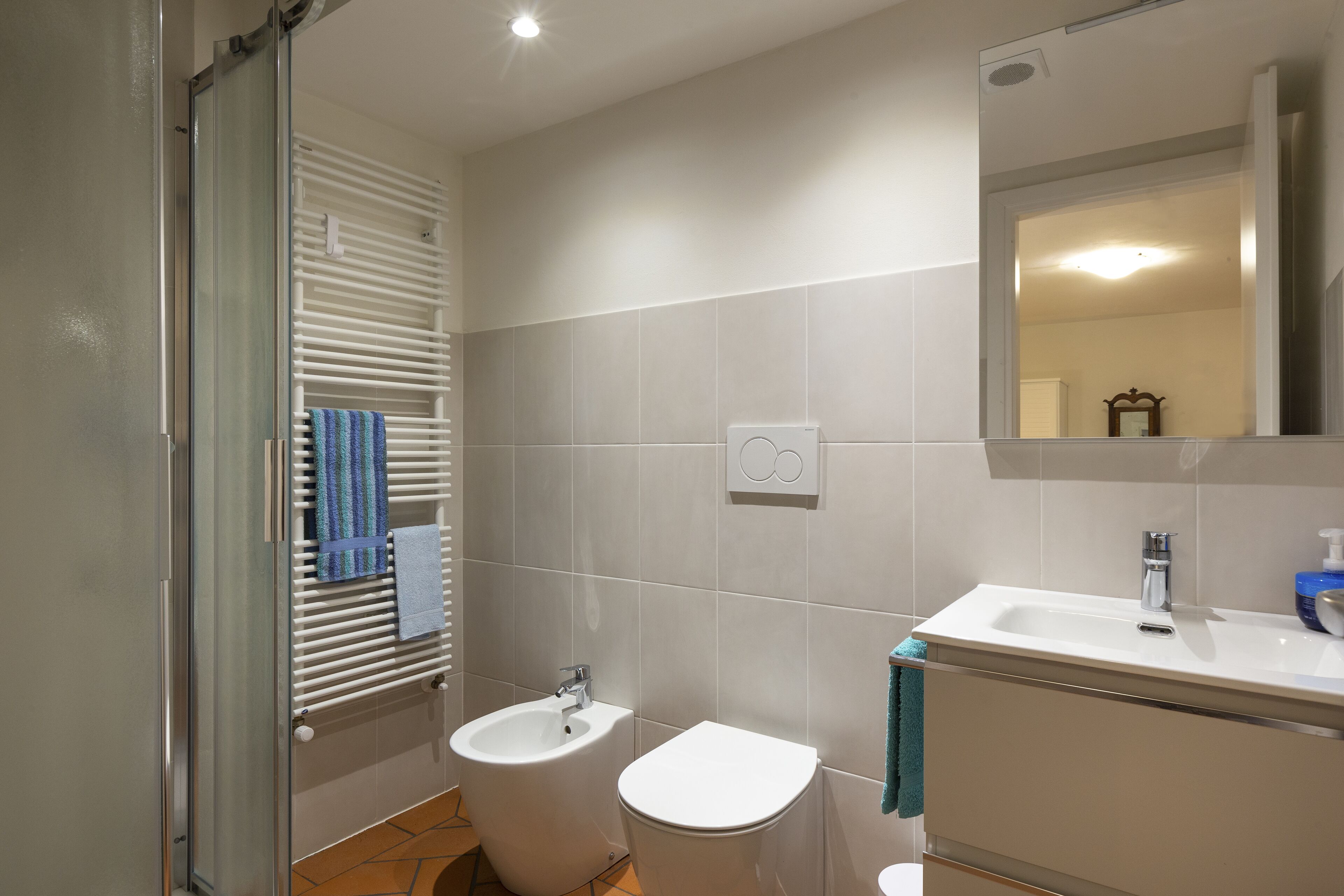A modern bathroom with a bidet, a sink, and a mirror.