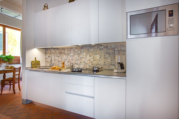 A modern kitchen with white cabinetry, a patterned backsplash, and a built-in microwave. - La Chapelle—a small, old country church (GRASSINA)